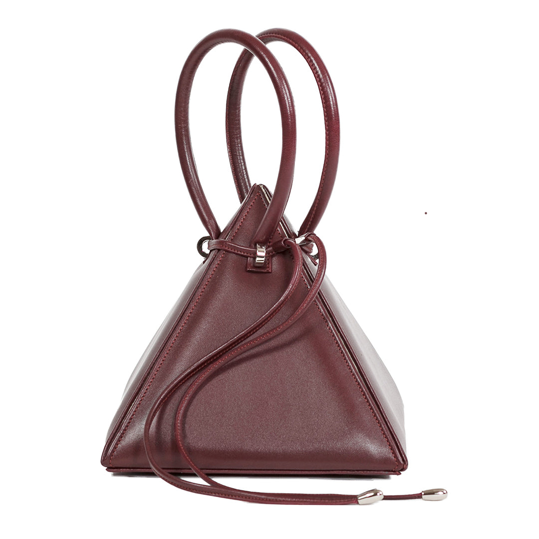 Buy now the Iconic Lia Handbag inspired by the geometric shapes of our designer's birth city Barcelona, and its world known artist, Antonio Gaudí, architect of the world wonder La Sagrada Familia. The Iconic Lia Burgundy Handbag has a unique and functional pyramidal design able to fit all your essentials.