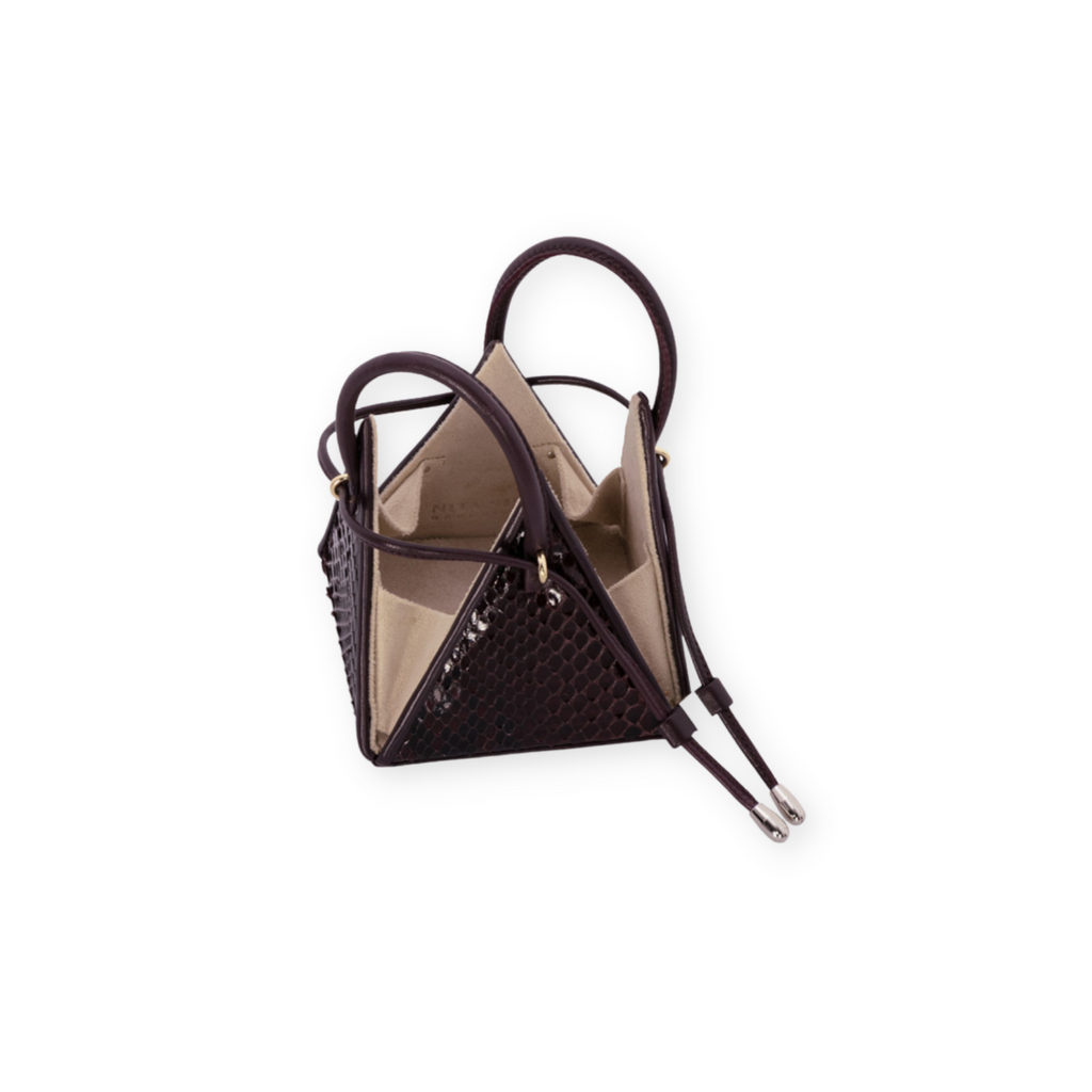 Buy now the Exotic LIA Mini bag inspired by the geometric shapes of our designer's birth city Barcelona, and its world known artist, Antonio Gaudí, architect of the world wonder La Sagrada Familia. The Exotic Lia Python Burgundy Mini bag has a unique and functional pyramidal design able to fit all your essentials.