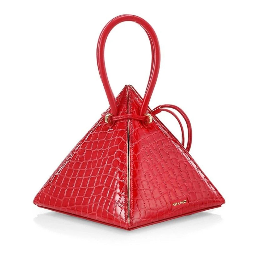 Buy now the Exotic Lia Handbag inspired by the geometric shapes of our designer's birth city Barcelona, and its world known artist, Antonio Gaudí, architect of the world wonder La Sagrada Familia. The Exotic Lia Croc-Embossed Passion Red Handbag has a unique and functional pyramidal design able to fit all your essentials. 