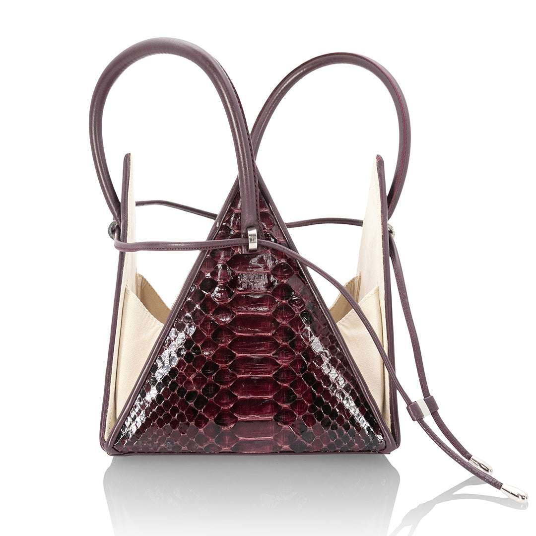 Buy now the Exotic Lia Handbag inspired by the geometric shapes of our designer's birth city Barcelona, and its world known artist, Antonio Gaudí, architect of the world wonder La Sagrada Familia. The Exotic Lia Python Burgundy Handbag has a unique and functional pyramidal design able to fit all your essentials. 