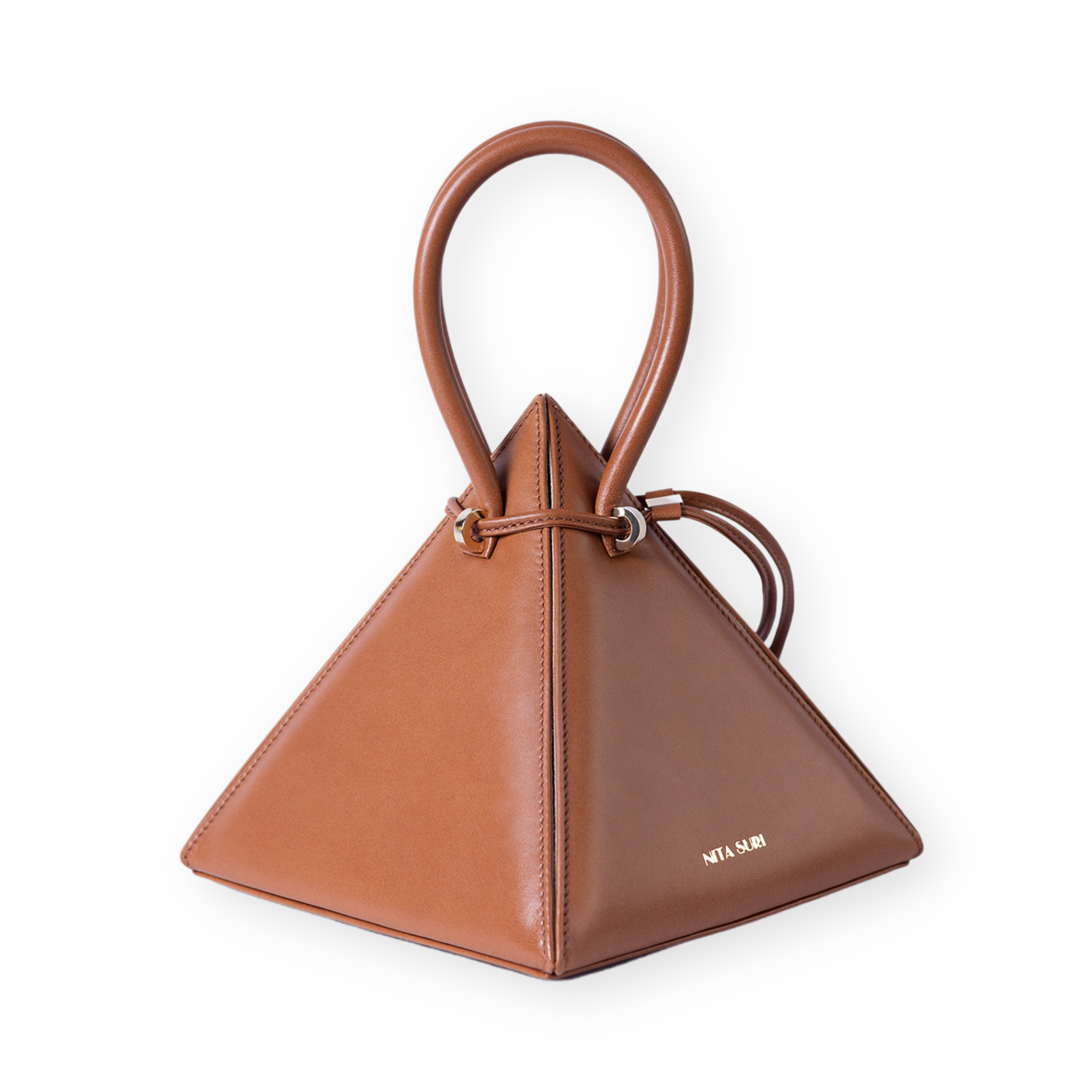 Buy now the Iconic Lia Handbag inspired by the geometric shapes of our designer's birth city Barcelona, and its world known artist, Antonio Gaudí, architect of the world wonder La Sagrada Familia. The Iconic Lia Cuero Tan Handbag has a unique and functional pyramidal design able to fit all your essentials. 