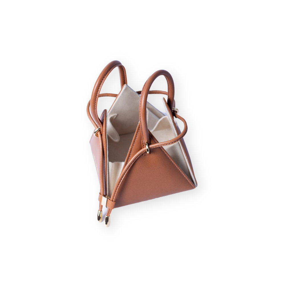 Buy now the Iconic LIA Mini bag inspired by the geometric shapes of our designer's birth city Barcelona, and its world known artist, Antonio Gaudí, architect of the world wonder La Sagrada Familia. The Iconic Lia Cuero Tan Mini bag has a unique and functional pyramidal design able to fit all your essentials. 