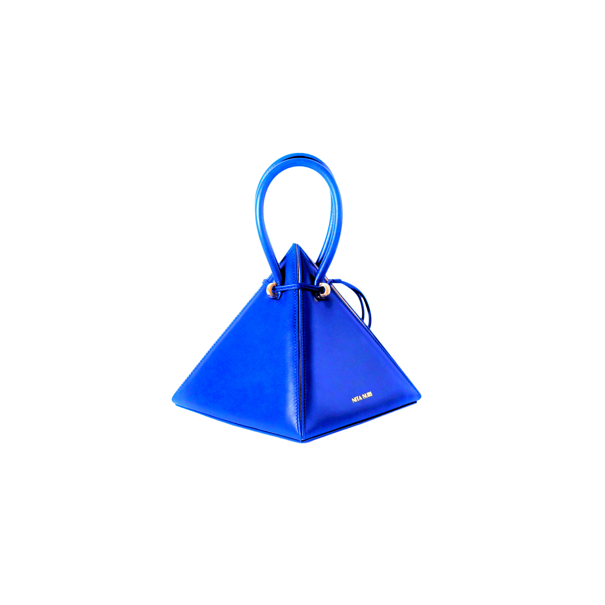 Buy now the Iconic LIA Mini bag inspired by the geometric shapes of our designer's birth city Barcelona, and its world known artist, Antonio Gaudí, architect of the world wonder La Sagrada Familia. The Iconic Lia Electric Blue Mini bag has a unique and functional pyramidal design able to fit all your essentials. 